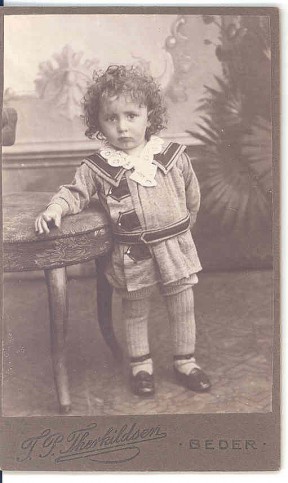 Sønnen Anker f. 1909 er fotograferet i 1911 af F.P. Therkildsen, Beder, i sit fi ne tøj - kort kjole med blonder i halsen, korte bukser, lange strømper og sko med rem om anklen.
