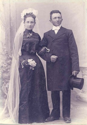 Bryllupsbillede 1903 Jakob og Kirsten Kristensen. Bruden er i sort med handsker, høj hals, snæver talje og vidde i kjolen. Jakob er i lang frakke, høj hat og hvid kravat i halsen.